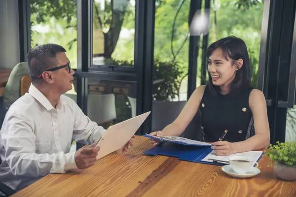 Two businesspeople meeting team discuss using laptop look at financial graph chart in office desk. Two young businessman reading Planning analyze marketing infographic. Partners team working together