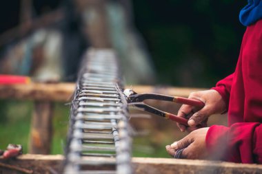 Kerpeten kullanan inşaat işçisi elleri demir tel kullanıyor. Açık hava işçisi, kerpeten kullanıyor, inşaat işlerinde çalışıyor. Erkekler elleri büküyor çelik telleri kesiyor beton işçiliğini destekliyor.