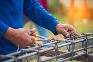 Kerpeten kullanan inşaat işçisi elleri demir tel kullanıyor. Açık hava işçisi, kerpeten kullanıyor, inşaat işlerinde çalışıyor. Erkekler elleri büküyor çelik telleri kesiyor beton işçiliğini destekliyor.