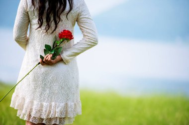 Sevgililer Günü 'nde sürpriz bir çift olmak için elinde gül çiçeği olan kadın dikiz aynasının arkasına saklanıyor. Güzel kadın yeşil parkta kırmızı gül çiçekçisine sürpriz yapıyor. Sevgililer Günü konsepti