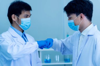 İki Asyalı bilim adamı yumruk tokuşturup takım arkadaşı oluyor. Ekip Adamları bilim kimyası araştırması laboratuvarda başarıyla çalışıyor. El farmasötik bilimi kurumsal ortaklığını kapatın.