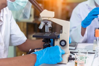 Bilim adamı bilim laboratuarındaki mikroskop araştırmalarını inceliyor. Asyalı bilim adamı laboratuvar kimya laboratuvarlarını arıyor. Covid-19 Coronavirus biyokimya araştırma deneyi aşı konsepti