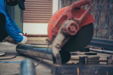 İnşaat işçisi elleri kaynak makineleri ile metal kıvılcımlar saçıyor. Erkek elleri koruyucu eldiven giyer. Alev metali, ateş demiri atölyesini keser. Çilingir kaynak makinesi kullanarak metal işlemini kesti