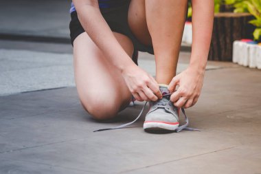 Genç bayanın diz çöktüğü spor ayakkabıları ayakkabı bağcıklarını bağla. Spor egzersiz koşucusu olarak koşu ayakkabılarını hazırla. El sıkışın, spor salonunda koşan ayakkabı bağcıklarını bağlayın sağlıklı bir yaşam tarzınız olsun..