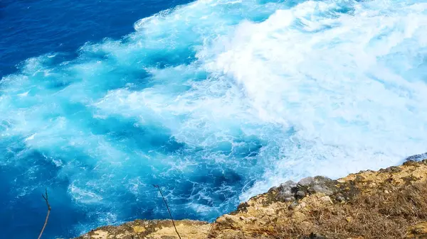 Turquoise ocean sea water white wave pattern splashing deep blue sea. Seascape dark ocean background wave splash on rock. Tropical sea beach in summer seaside outdoor. Water Surface blue wave pattern