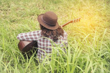 Yeşil parkta akustik gitar çalan genç kadınlar. Evde akustik gitar enstrümanı çalan bir kadın, güzel doğada genç Asyalı müzisyen kız yaşam tarzı. Mutlu gitarist