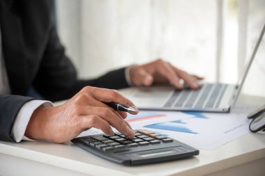 Yakın plan Asyalı işadamına hesap numarasını, iş planlama raporunu, Asyalı iş adamının ellerini hesap makinesi kullanarak hesap makinesini, vergi faturasını verdi. Vergi denetimi finans kavramı