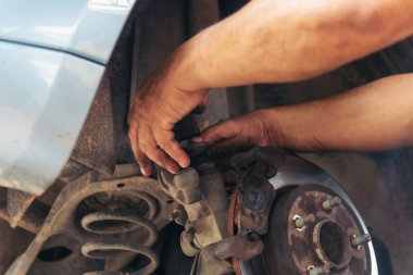 Tamirci araba tamirhanesini kapatırken araba tamircisini de eline aldı. Makineli araç mekanik servisini tamir eden adam elleri. Araç kaputu otomobili kontrol ediyor. Araç bakım mühendisi.