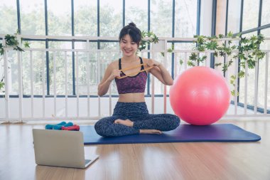 Beautiful Asian Women use dumbbell exercises for muscle-building home fitness. Women weight training smile use exercise pilates ball dumbbell. Beauty woman smiling sportswear on yoga mat home fitness