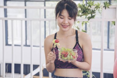 Sağlıklı Asyalı kadınlar organik yeşil salata sebze yemeği giyiyorlar. Güzel bir kız vejetaryen sağlık yaşam tarzı konsepti. Sağlıklı bir kadın organik salata kasesini sağlıklı bir yaşam tarzında tutuyor.