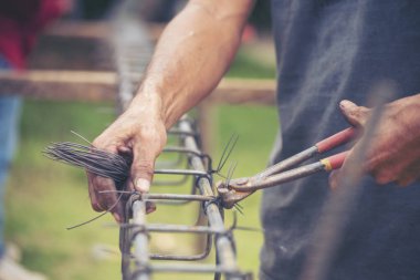 Kerpeten kullanan inşaat işçisi elleri demir tel kullanıyor. Açık hava işçisi, kerpeten kullanıyor, inşaat işlerinde çalışıyor. Erkekler elleri büküyor çelik telleri kesiyor beton işçiliğini destekliyor.
