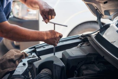 Tamirci araba tamirhanesini kapatırken araba tamircisini de eline aldı. Makineli araç mekanik servisini tamir eden adam elleri. Araç kaputu otomobili kontrol ediyor. Araç bakım mühendisi.