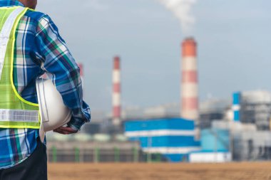 Elektrik santrallerinde elektrik santrali üretirken elinde beyaz başlık tutan bir mühendis. Teknisyen işçi mavi kasklı mühendis buhar bacası endüstrisi geçmişi var.
