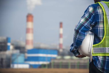 Elektrik santrallerinde elektrik santrali üretirken elinde beyaz başlık tutan bir mühendis. Teknisyen işçi mavi kasklı mühendis buhar bacası endüstrisi geçmişi var.
