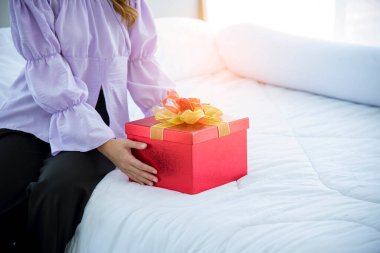 Kadın sürprizi Noel arifesinde hediye kutusunu aldı. Asyalı bir kadın Noel ağacının altında gülen yüzlü bir hediye kutusu tutuyor. Kadın eli hediyeyi paketler. Mutlu noeller Yeni yıl konsepti