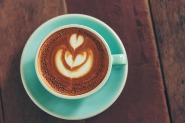 Sütlü, ahşap masadaki Latte sanat kahve fincanı. Espresso shot 'la sütlü kahve fincanı yapılır. İtalyan kafeteryasında sütlü kapuçino. Kafeteryada fotokopi alanı olan kahverengi kahve içeceği.