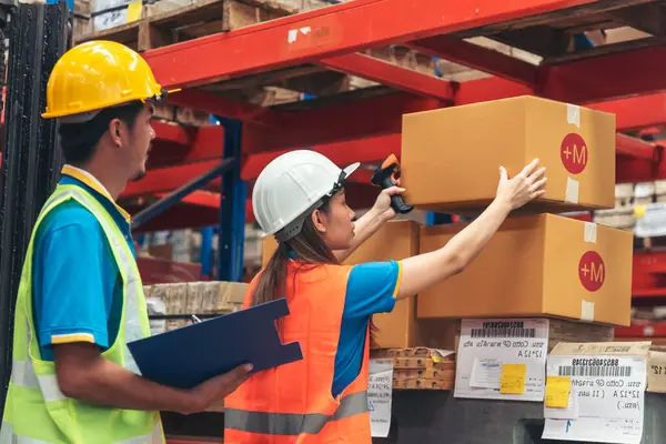 Warehouse management team use bar code scaner scan goods shelf writing checklist on clipboard. Asian men women worker check stock inventory. Teamwork logistics staff counting products store inventory