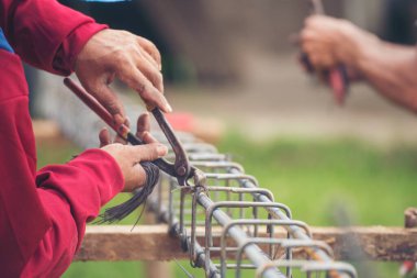 Kerpeten kullanan inşaat işçisi elleri demir tel kullanıyor. Açık hava işçisi, kerpeten kullanıyor, inşaat işlerinde çalışıyor. Erkekler elleri büküyor çelik telleri kesiyor beton işçiliğini destekliyor.