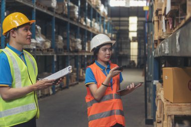 Depo yönetimi stok envanterini kontrol ediyor. Asyalı kadın işçi kadın barkod tarayıcı kullanıyor. Mal raflarını tarıyor ve listeyi panoya yazıyor. Ekip çalışması lojistik personeli ürün depolama envanterini sayıyor