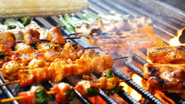 Barbekü ızgara et çubuğu ateşte, dışarıda da sıcak kömür var. Parti için domuz pastırmalı sosisli ızgara piknik. Izgara domuz eti ateşte yanıyor.