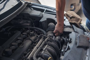 Tamirci araba tamirhanesini kapatırken araba tamircisini de eline aldı. Makineli araç mekanik servisini tamir eden adam elleri. Araç kaputu otomobili kontrol ediyor. Araç bakım mühendisi.