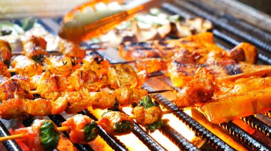 Barbekü ızgara et çubuğu ateşte, dışarıda da sıcak kömür var. Parti için domuz pastırmalı sosisli ızgara piknik. Izgara domuz eti ateşte yanıyor.