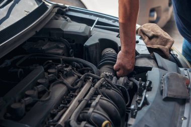 Tamirci araba tamirhanesini kapatırken araba tamircisini de eline aldı. Makineli araç mekanik servisini tamir eden adam elleri. Araç kaputu otomobili kontrol ediyor. Araç bakım mühendisi.