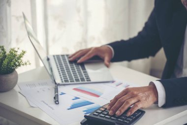 Yakından çalışan işadamları ofis masasında dizüstü bilgisayar finansmanı iş belgelerini kullanarak rapor tablosu okuyorlar. Adam elleri klavye yazın ofis nota kontrol mali grafik grafiği