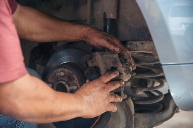 Tamirci araba tamirhanesini kapatırken araba tamircisini de eline aldı. Makineli araç mekanik servisini tamir eden adam elleri. Araç kaputu otomobili kontrol ediyor. Araç bakım mühendisi.