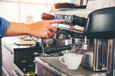 Close up hands coffee barista man make hot cup espresso shot from coffee machine. Cappuccino with milk in italian coffee shop cafe. Close up hands of barista use machine make black drinking hot cup