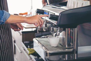 Close up hands coffee barista man make hot cup espresso shot from coffee machine. Cappuccino with milk in italian coffee shop cafe. Close up hands of barista use machine make black drinking hot cup