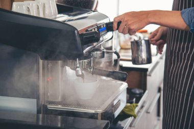Close up hands coffee barista man make hot cup espresso shot from coffee machine. Cappuccino with milk in italian coffee shop cafe. Close up hands of barista use machine make black drinking hot cup