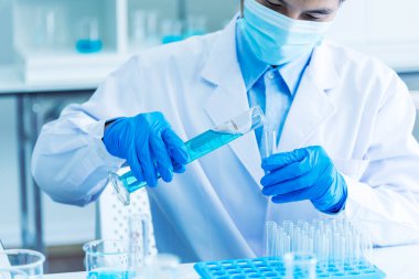 Scientist man holding sample blood test tube in science laboratory. Doctor clinic healthcare technician lab testing blood sample diagnosis. Asian man scientist working in hiv testing medical lab.