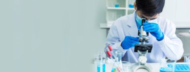 Banner Scientist bilim laboratuarında mikroskop araştırmasına bakıyor. Banner Asyalı bilim adamı laboratuvar ekipmanları kimya laboratuvarında mikrobiyoloji mikroskobu kullanıyor. Kopya alanı ile biyokimya deneyi