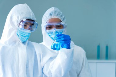 İki Asyalı bilim adamı kimya bilimi tüpü deney tüpü antikor örneğini kovid-19 virüsüne karşı laboratuvar geliştirmek için depoluyorlar. Kimya Laboratuarı 'nda bilim adamı danışmanı, analizi