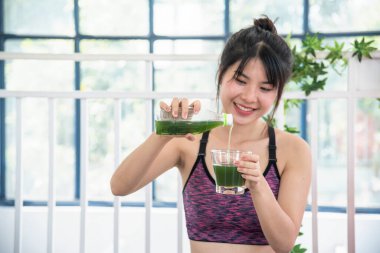Kadın elleri elinde smoothie detox yeşil meyve suyu taze taze meyve suyu soğuk içecek tutuyor. Asyalı kadınlar, vejetaryen sebze suyu içerken gülümserler. Kereviz suyu döken kadın kokteyl bardağı içiyor.