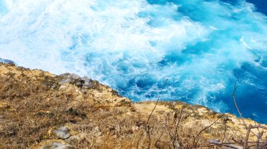 Turkuaz okyanus suyu beyaz dalga açık mavi deniz. Kuş bakışı canavar dalgası kayaya çarpıyor. Yazın açık deniz sahillerinde tropik deniz plajı. Okyanus adası güzel dramatik manzara.