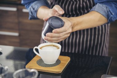 Kahve barmeni espresso doldurur ve sıcak kahve fincanı yapar. İtalyan kafeteryasında sütlü kapuçino. Kahvecinin ellerini kapat. Müşteri kafeteryası için kahverengi latte sanatı yap..