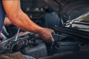 Tamirci araba tamirhanesini kapatırken araba tamircisini de eline aldı. Makineli araç mekanik servisini tamir eden adam elleri. Araç kaputu otomobili kontrol ediyor. Araç bakım mühendisi.