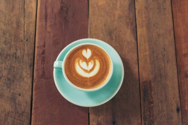 Sütlü, ahşap masadaki Latte sanat kahve fincanı. Espresso shot 'la sütlü kahve fincanı yapılır. İtalyan kafeteryasında sütlü kapuçino. Kafeteryada fotokopi alanı olan kahverengi kahve içeceği.