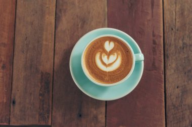 Sütlü, ahşap masadaki Latte sanat kahve fincanı. Espresso shot 'la sütlü kahve fincanı yapılır. İtalyan kafeteryasında sütlü kapuçino. Kafeteryada fotokopi alanı olan kahverengi kahve içeceği.