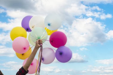 Yeşil çayır üzerinde koşan balonlar tutan neşeli şirin kız beyaz bulut ve mutlulukla mavi gökyüzü. Hava balonları tutan eller doğum günü partisinde oynar. Mutlu zamanlar yaz mevsimi açık havada.