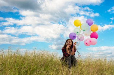 Yeşil çayır üzerinde koşan balonlar tutan neşeli şirin kız beyaz bulut ve mutlulukla mavi gökyüzü. Hava balonları tutan eller doğum günü partisinde oynar. Mutlu zamanlar yaz mevsimi açık havada.
