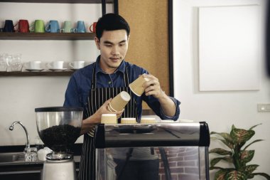 Kahve yapan adam kahve makinesinden espresso shot yapıyor. İtalyan kafeteryasında sütlü kapuçino. Kahve makinesinin ellerini kapat. Müşteri kafeteryası için kahverengi latte yap.