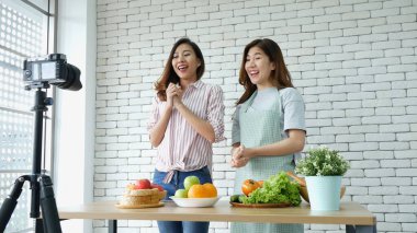 İki Asyalı vlogcu birlikte sağlıklı bir yaşam tarzı gözden geçiriyorlar. İki Genç Kadın Arkadaş blogcusu Mutlu Yaşam Biçimi Canlı Yayın. İki kadın sosyal medyadan konuşuyor, merhaba de.
