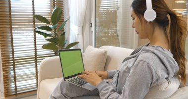 Boş Yeşil Ekran dizüstü bilgisayar blogcusu kadının elleri dizüstü bilgisayarda klavye kullanıyor. Dizüstü bilgisayarlı kanepe oturma odasını kullanarak kadın ellerini kapat. Serbest çalışan kadınlar ev içi video konferansında çalışıyorlar.