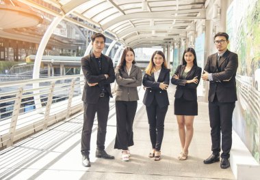 Portrait Group of businesspeople arms crossed smiling look at camera in modern city background. Happy Businessman, businesswoman teams partnership. Business people teams positive teamwork standing.