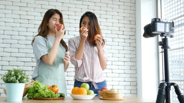 Asyalı vlogger canlı yayında sağlıklı beslenme tarzı hakkında yorum yapıyor. İki genç bayan arkadaş blogcu mutlu bir yaşam tarzı sunuyor. Sebze, meyve, vejetaryen ürünleri nasıl yenir. İki kadın sosyal medya vlog 'undan bahsediyor