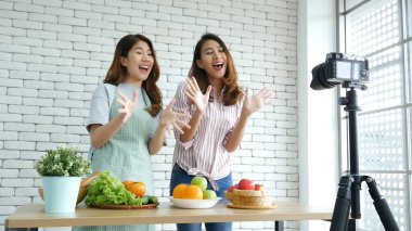 Asyalı vlogger canlı yayında sağlıklı beslenme tarzı hakkında yorum yapıyor. İki genç bayan arkadaş blogcu mutlu bir yaşam tarzı sunuyor. Sebze, meyve, vejetaryen ürünleri nasıl yenir. İki kadın sosyal medya vlog 'undan bahsediyor