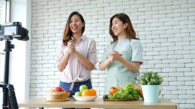 Asyalı vlogger canlı yayında sağlıklı beslenme tarzı hakkında yorum yapıyor. İki genç bayan arkadaş blogcu mutlu bir yaşam tarzı sunuyor. Sebze, meyve, vejetaryen ürünleri nasıl yenir. İki kadın sosyal medya vlog 'undan bahsediyor